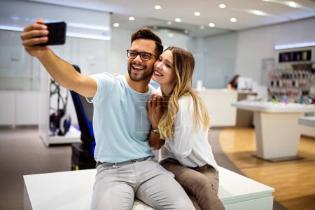 Photo for Smiling young couple have fun using smartphone together, happy caucasian man and woman watch video on cellphone, make self-portrait picture on cell - Royalty Free Image