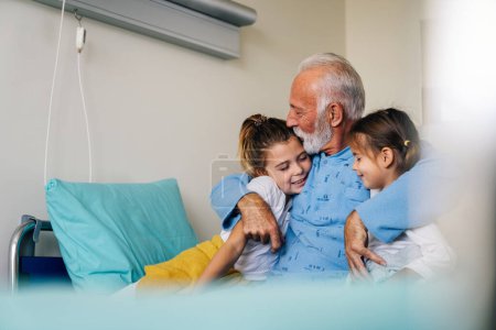 Photo for Medicine, support, family, healthcare and people concept. Happy grandchildren visiting her grandfather at hospital ward - Royalty Free Image