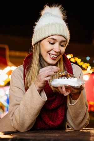 Photo for Portrait of happy woman girl eating donuts and enjoying christmas market. Holiday christmas people fun concept - Royalty Free Image
