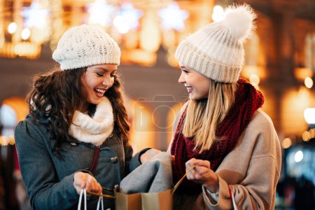 Téléchargez les photos : Des amies heureuses achètent des cadeaux à Noël. Personnes Noël vente de vacances concept shopping - en image libre de droit