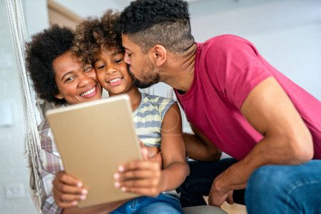Photo for Happy african family having fun with device at home, black parents and child using digital tablet looking at screen together. - Royalty Free Image