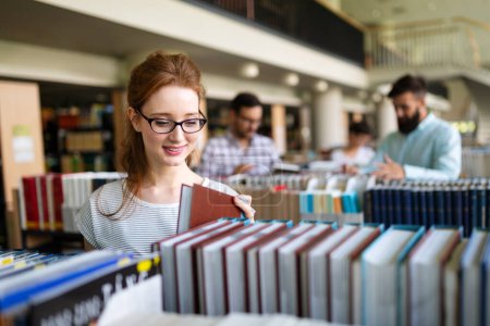 Photo for Happy young university students studying with books in library. Group of multiracial people in college - Royalty Free Image
