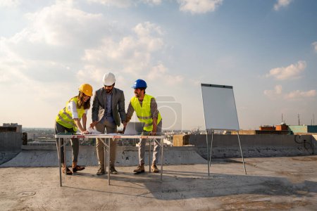 Photo for Team of architects people in group on construciton site checking documents and business workflow - Royalty Free Image