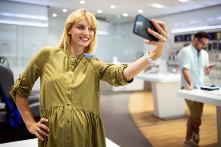 Foto de Primer plano de una joven mujer en una tienda de tecnología, explorando un nuevo teléfono inteligente. Concepto de personas de comunicación de dispositivos digitales. - Imagen libre de derechos