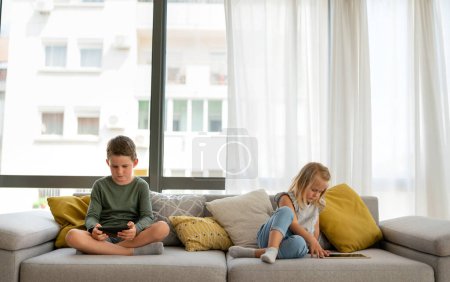 Photo for Portrait of happy children using digital devices and having fun together. Kid technology addiction concept. - Royalty Free Image