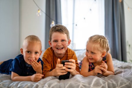 Foto de Retrato de niños felices usando dispositivos digitales y divirtiéndose juntos. Concepto de adicción a la tecnología infantil. - Imagen libre de derechos