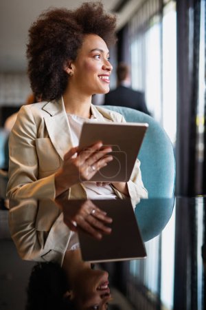 Téléchargez les photos : Portrait d'une jeune femme d'affaires afro-américaine intelligente utilisant sa tablette numérique au bureau - en image libre de droit