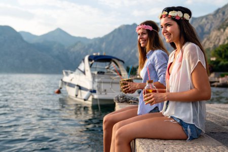 Foto de Chicas felices divirtiéndose tomando cócteles en la playa en las vacaciones de verano. La gente viaja concepto divertido - Imagen libre de derechos