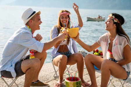 Foto de Grupo de amigos felices divirtiéndose con cócteles tropicales en la fiesta de playa. Concepto de viajes y vacaciones de verano. - Imagen libre de derechos