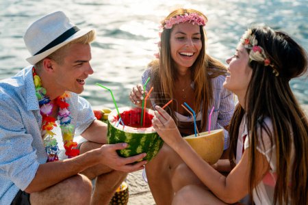 Foto de Felices jóvenes amigos divirtiéndose con cócteles tropicales en la fiesta de playa. Concepto de viajes y vacaciones de verano. - Imagen libre de derechos