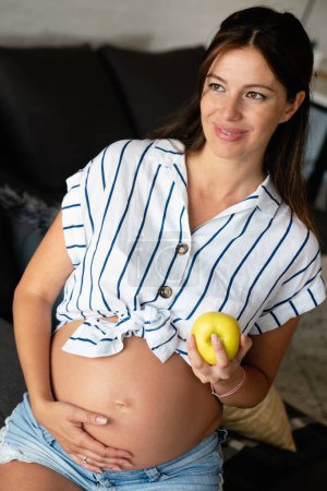 Téléchargez les photos : Nutrition et alimentation pendant la grossesse. Une jeune femme enceinte prête attention aux aliments sains et aux vitamines - en image libre de droit