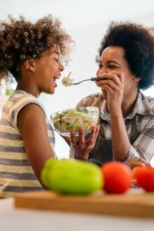 Foto de Comida saludable, concepto familiar y de personas. Feliz madre e hija desayunando en casa cocina - Imagen libre de derechos