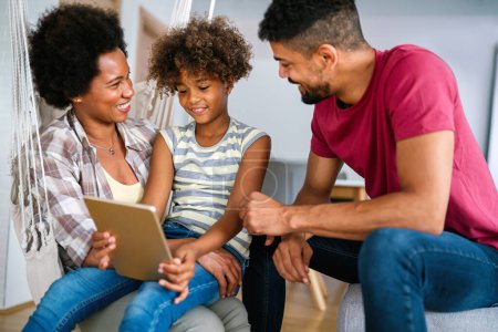 Photo for Happy african family having fun with device at home, black parents and child using digital tablet looking at screen together. - Royalty Free Image