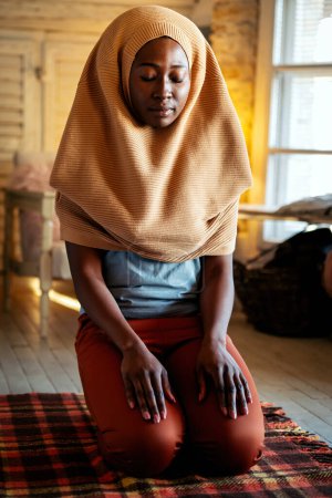 Téléchargez les photos : Jeune musulmane noire priant à la maison. Concept de religion populaire - en image libre de droit