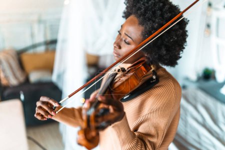 Téléchargez les photos : Jolie jeune musicienne noire joue du violon pratiquant l'instrument de musique à la maison - en image libre de droit
