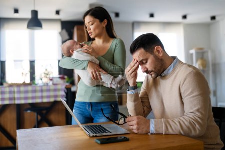 Photo for Father businessman try to work on laptop from home with wife and baby on background. Work from home concept. Freelancer - Royalty Free Image