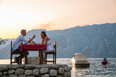 Foto de Una pareja está teniendo una cena privada en una playa tropical durante el atardecer. Concepto de viaje de luna de miel - Imagen libre de derechos