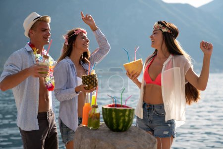 Téléchargez les photos : Groupe d'amis heureux s'amuser avec des cocktails tropicaux sur la fête de la plage. Voyage et vacances d'été concept. - en image libre de droit