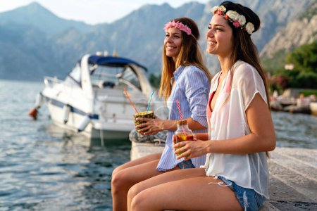 Téléchargez les photos : Filles heureuses, les femmes s'amusent avec des cocktails tropicaux sur la plage. Voyage et vacances d'été concept. - en image libre de droit