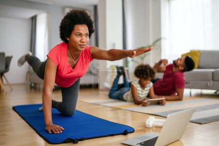 Photo for Sport yoga video streaming. Home fitness workout class live streaming online. Happy african american woman exercise at home. - Royalty Free Image