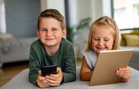 Foto de Niña y niño viendo vídeo o jugando juegos en su tableta dispositivo digital, teléfono inteligente. Concepto de adicción digital infantil. - Imagen libre de derechos