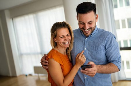 Téléchargez les photos : Portrait de couple heureux s'amusant, en utilisant le téléphone mobile ensemble. Concept de technologie des personnes - en image libre de droit