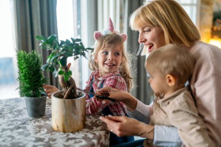 Téléchargez les photos : Petits enfants mignons avec mère prenant soin des plantes à l'intérieur. Amusement familial concept de jardinage à la maison. - en image libre de droit