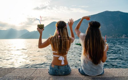 Foto de Chicas felices, mujeres divirtiéndose con cócteles tropicales en la playa. Concepto de viajes y vacaciones de verano. - Imagen libre de derechos