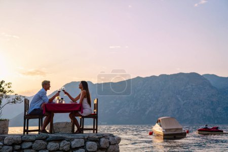 Foto de Una pareja está teniendo una cena privada en una playa tropical durante el atardecer. Gente verano vacaciones concepto. - Imagen libre de derechos