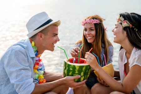 Foto de Jóvenes felices divirtiéndose en una fiesta en la playa. Grupo de amigos disfrutando de vacaciones de verano y viajes - Imagen libre de derechos