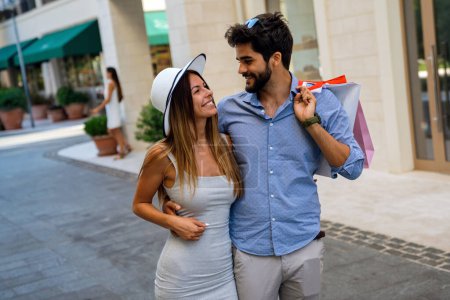 Photo for Beautiful young loving couple carrying shopping bags and enjoying travel, vacation together. Consumerism, people travel concept. - Royalty Free Image