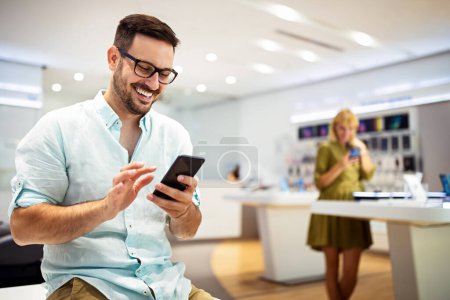 Photo for Happy man checking social media holding smart phone. Smiling young male using mobile phone app playing game, shopping online, ordering delivery - Royalty Free Image