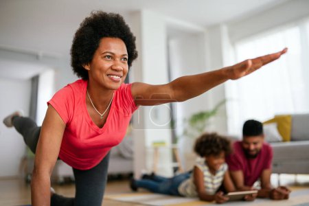 Téléchargez les photos : Femme afro-américaine avec de la famille sur fond de travail à la maison. Concept de forme physique et mode de vie sain. - en image libre de droit