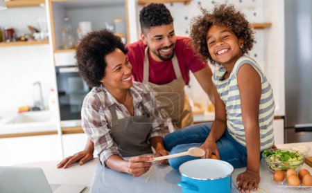 Overjoyed young african american family with kid have fun cooking at home together, happy smiling parents enjoy weekend play with child in kitchen