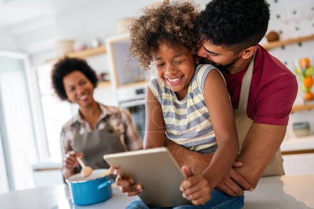 Foto de Familia africana feliz divirtiéndose con el dispositivo en casa, los padres negros y el niño usando la tableta digital mirando la pantalla juntos. - Imagen libre de derechos