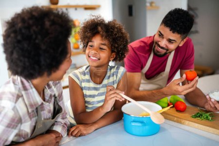 Happy african american parents and child having fun preparing healthy food in kitchen. Family happiness fun concept
