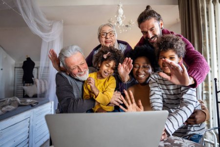 Téléchargez les photos : Joyeux rassemblement familial multigénération autour d'un ordinateur portable et s'amuser lors d'un appel vidéo - en image libre de droit