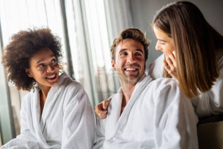 Gruppe fröhlicher multiethnischer Menschen, die Wellness genießen, entspannen sich am Wochenende. Mann mit zwei schönen Frauen im Schlafzimmer. Polyamory-Konzept