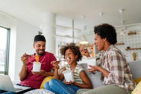 Téléchargez les photos : Famille maison delivary concept de nourriture à emporter. Heureuse famille afro-américaine manger dans le salon et profiter du temps ensemble. - en image libre de droit