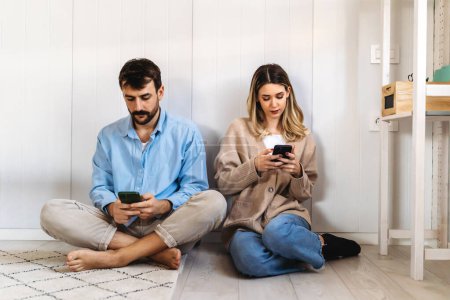 Photo for Couple addicted to smartphones ignoring each other at home. Relationship problems. Social media concept. - Royalty Free Image