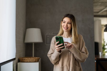 Foto de Niña usando suéter usando teléfono inteligente en casa, comunicación y concepto de red social, mujer navegando por Internet - Imagen libre de derechos