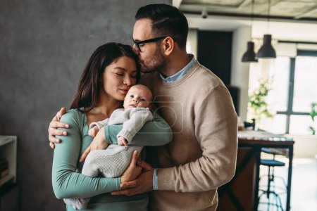 Photo for Portrait of young parents and newborn baby. Father and mother kiss and hug a beautiful newborn child. The concept of love, happy fatherhood and motherhood. - Royalty Free Image