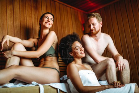 Enjoying a day of pampering. Group of multiethnic happy people, friends relaxing in the sauna together.
