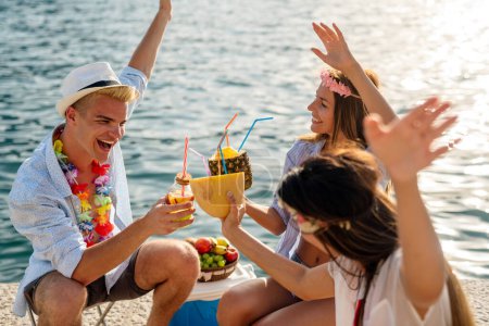 Téléchargez les photos : De jeunes amis heureux s'amusent avec des cocktails tropicaux sur la plage. Voyage et vacances d'été concept. - en image libre de droit