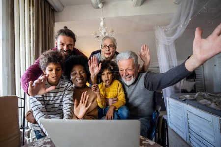 Foto de Extendió feliz familia multiétnica multigeneracional juntos en casa durante la videollamada. Gente felicidad tecnología concepto - Imagen libre de derechos