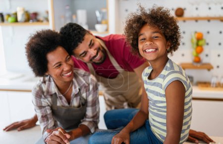 Happy african american parents and child having fun preparing healthy food in kitchen. Family happiness fun concept