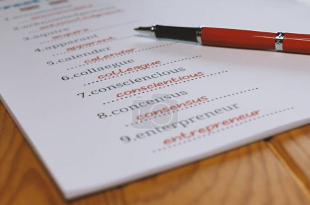 Feuille de calcul mal orthographiée anglaise avec stylo et tablette sur une table en bois au bureau