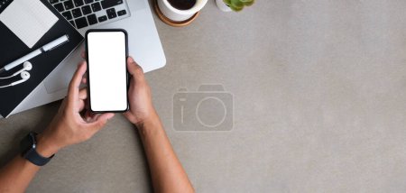 Photo pour Hands holding mobile phone over office desk. Copy space, blank screen for your advertise design or information content. - image libre de droit