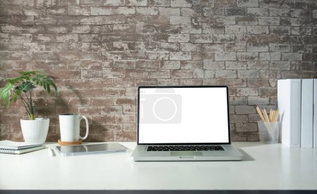 Photo for Home office interior with laptop computer, books, coffee cup and houseplant on white table. - Royalty Free Image