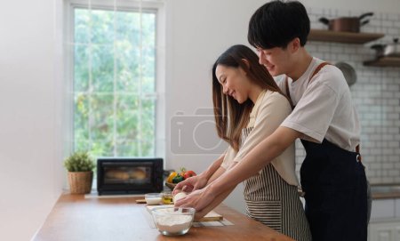 Photo for Beautiful young couple preparing meal, making fresh dough for breakfast in the kitchen . - Royalty Free Image